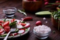 Fresh red radish in wooden bowl among plates with vegetables, herbs and spicies, top view, selective focus. Royalty Free Stock Photo