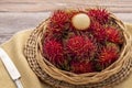 Fresh red rambutan fruits in a flat wicker basket