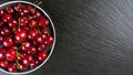 Fresh red ripe sweet cherry on plate on black slate background. Royalty Free Stock Photo