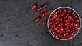 Fresh red ripe sweet cherry with water drops on plate on black slate background. Royalty Free Stock Photo