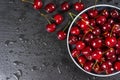 Fresh red ripe sweet cherry with water drops on plate on black slate background. Royalty Free Stock Photo