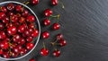 Fresh red ripe sweet cherry with water drops on plate on black slate background. Royalty Free Stock Photo