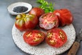 Fresh red ripe tomatoes on a wooden cutting board with black Thursday salt, dark rustic background. Tomatoes being cut Royalty Free Stock Photo