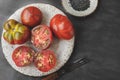 Fresh red ripe tomatoes on a wooden cutting board with black Thursday salt, dark rustic background. Tomatoes being cut Royalty Free Stock Photo