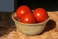 Fresh red round tomatoes in a bowl on the woven table Royalty Free Stock Photo