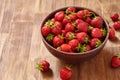 Fresh red strawberries in a brown clay bowl on wooden table. Royalty Free Stock Photo