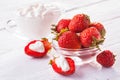 Fresh red strawberries with cream on the white wooden table.