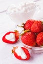 Fresh red strawberries with cream on the white wooden table.