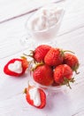 Fresh red strawberries with cream on the white wooden table.