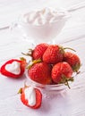 Fresh red strawberries with cream on the white wooden table.