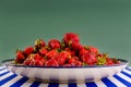Fresh red strawberries on a faience dish on a green background.
