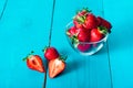 Fresh red strawberries in transparent bowl and small kitchen towel in blue wooden background Royalty Free Stock Photo