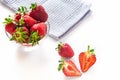 Fresh red strawberries in transparent bowl and small kitchen towel isolated on white background Royalty Free Stock Photo