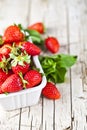 Fresh red strawberries in white bowl and mint leaves on rustic wooden background Royalty Free Stock Photo