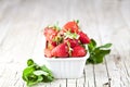Fresh red strawberries in white bowl and mint leaves on rustic wooden background Royalty Free Stock Photo
