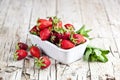 Fresh red strawberries in white bowl and mint leaves on rustic wooden background Royalty Free Stock Photo