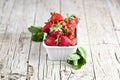 Fresh red strawberries in white bowl and mint leaves on rustic wooden background Royalty Free Stock Photo