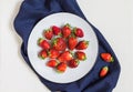 Fresh red strawberries on a white plate on a natural background of white clay.