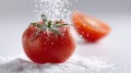 Fresh red tomato covered with coarse salt crystals falling on white surface. Culinary ingredient preparation concept with Royalty Free Stock Photo