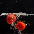 Fresh red tomato falling into water with water splash and air bubbles isolated on black background Royalty Free Stock Photo