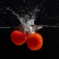 Fresh red tomato falling into water with water splash and air bubbles isolated on black background Royalty Free Stock Photo