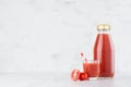 Fresh red tomato juice in glass bottle mock up with glass, straw, vegetables slices in soft light white interior on wood table.