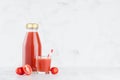 Fresh red tomato juice in glass bottle mock up with glass, straw, vegetables slices in soft light white interior on wood table.