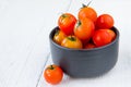 Fresh red tomatoes in black bowl on white wooden table Royalty Free Stock Photo