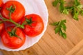 Fresh red tomatoes close up on a white plate at a wooden board with green parsley Royalty Free Stock Photo