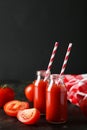 Fresh red tomatoes and juice in bottles on the black background Royalty Free Stock Photo