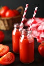 Fresh red tomatoes and juice in bottles on the black background Royalty Free Stock Photo