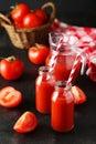 Fresh red tomatoes and juice in bottles and jug on the black background Royalty Free Stock Photo