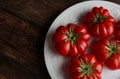 Fresh red tomatoes raf, on white plate on wooden background. Food concept Royalty Free Stock Photo