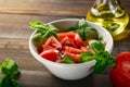 Fresh red tomatoes are sliced in a white ceramic plate with basil herb and olive oil on a wooden table Royalty Free Stock Photo