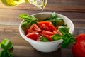 Fresh red tomatoes are sliced in a white ceramic plate with basil herb and olive oil on a wooden table Royalty Free Stock Photo