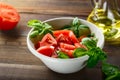 Fresh red tomatoes are sliced in a white ceramic plate with basil herb and olive oil on a wooden table Royalty Free Stock Photo