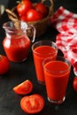 Fresh red tomatoes and tomato juice in glass and jug on the black background Royalty Free Stock Photo