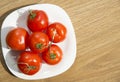 Fresh red tomatoes in white plate on wooden table Royalty Free Stock Photo