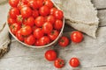 Fresh red tomatoes in a wicker basket on an old wooden table. Ripe and juicy cherry tomatoes with drops of moisture, gray wooden Royalty Free Stock Photo
