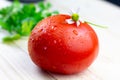 Fresh tomatoes with waterdrops and parsley and chamomile on a wooden table Royalty Free Stock Photo