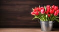 Fresh red tulip flowers bouquet in a metal bucket on a shelf in front of wooden wall Royalty Free Stock Photo