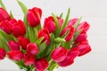 Fresh red tulip flowers bouquet on shelf in front of wooden wall Royalty Free Stock Photo
