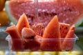 Fresh red watermelon fruit cut in tray ready to eat with clear fork selling in local market blurred background, selective focus Royalty Free Stock Photo