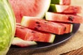 Fresh red watermelon pieces on a black plate on a wooden table. Sweet and juicy watermelon Royalty Free Stock Photo