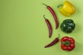 Fresh red, yellow and green bell peppers and chili peppers on a green background. Top view Royalty Free Stock Photo