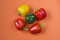 Fresh red, yellow and green bell peppers on an orange background. Top view Royalty Free Stock Photo