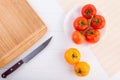 Fresh red and yellow tomatoes from above on a white textured table with a board and a knife Royalty Free Stock Photo