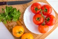 Fresh red and yellow tomatoes from above on a wooden board with a knife in a white plate at a white table Royalty Free Stock Photo