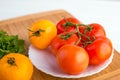 Fresh red and yellow tomatoes close up on a wooden board at a white table Royalty Free Stock Photo