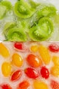 Fresh red, yellow tomatoes and green tomato slices frozen in an ice cube on white background. Studio shot. Royalty Free Stock Photo